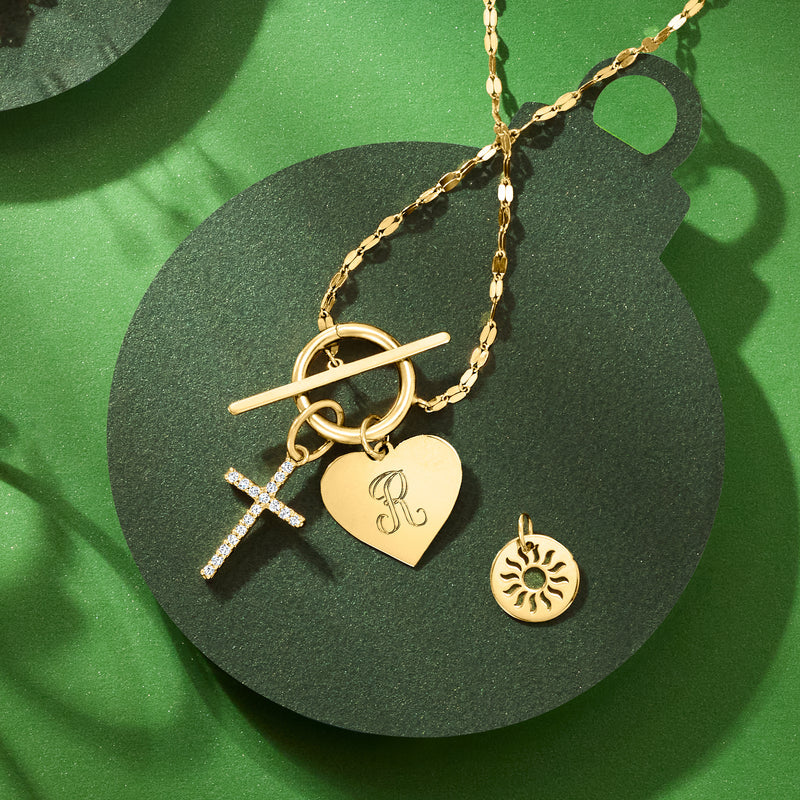 Yellow gold sun disc charm with cut-out rays on a charm necklace chain