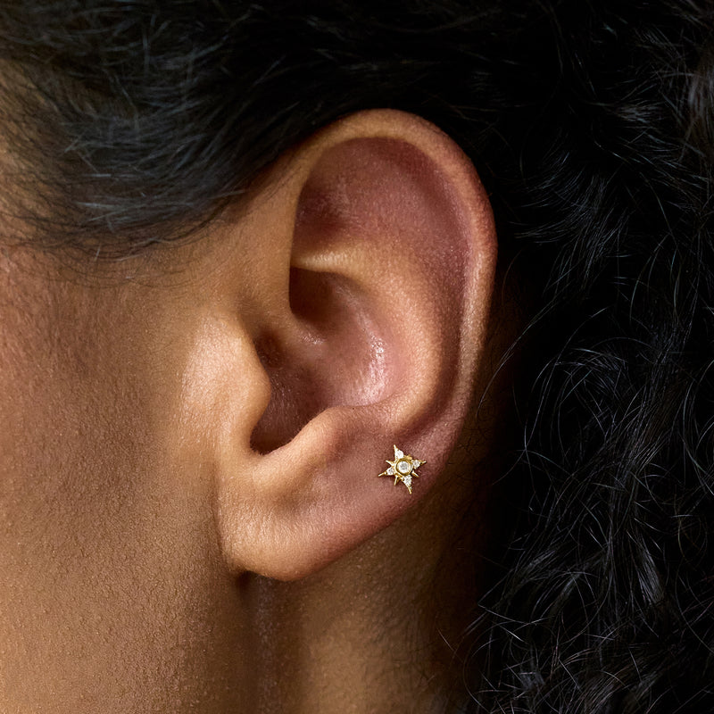 Close-up of star diamond stud earrings in 14kt yellow gold on ear