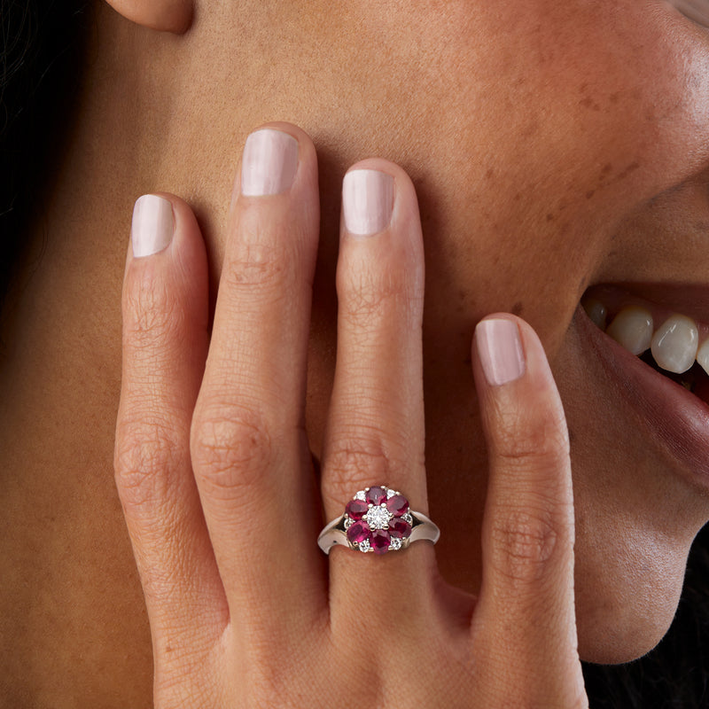 Ruby and diamond flower ring on finger with white gold band