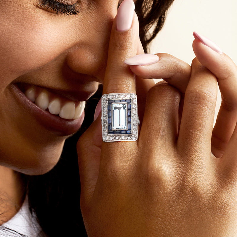 Platinum vintage gemstone ring on finger with rectangular aquamarine, blue sapphires, diamonds