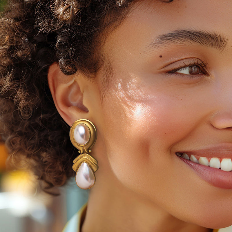Mabe pearl clip-on drop earrings in yellow gold, worn close-up with two pearls