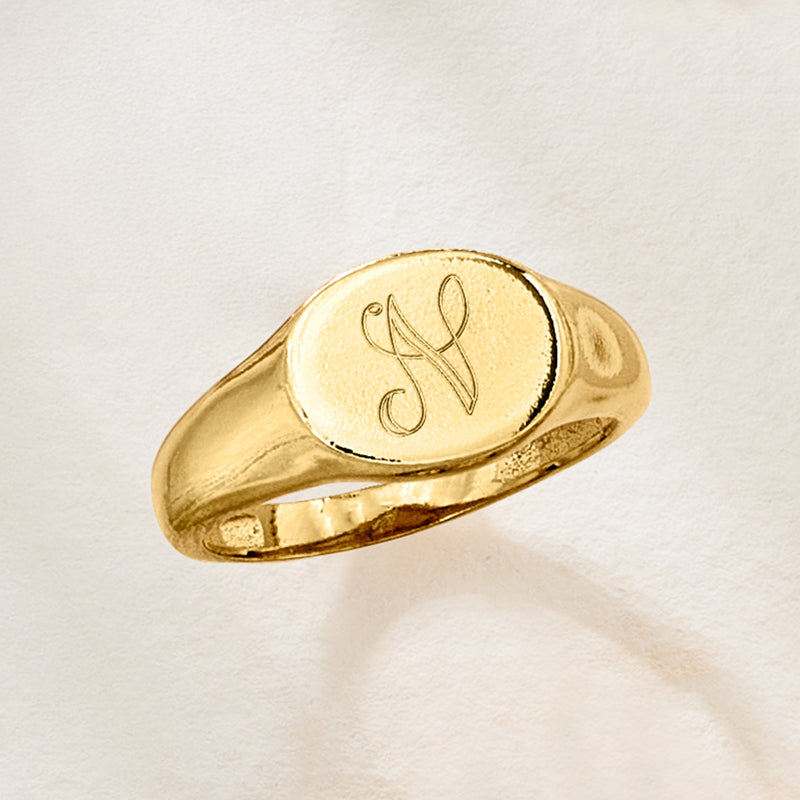 Personalized oval signet ring, gold-tone oval face with engraved monogram; angled top view