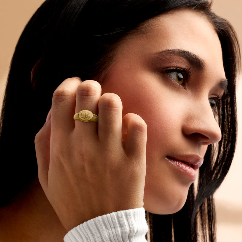 Personalized oval signet ring in gold-tone, worn on finger with engraved oval monogram