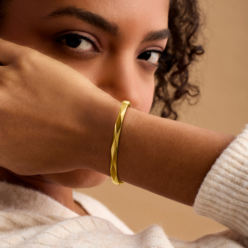 Gold vermeil geometric bangle bracelet on wrist, wide hinged cuff with texture