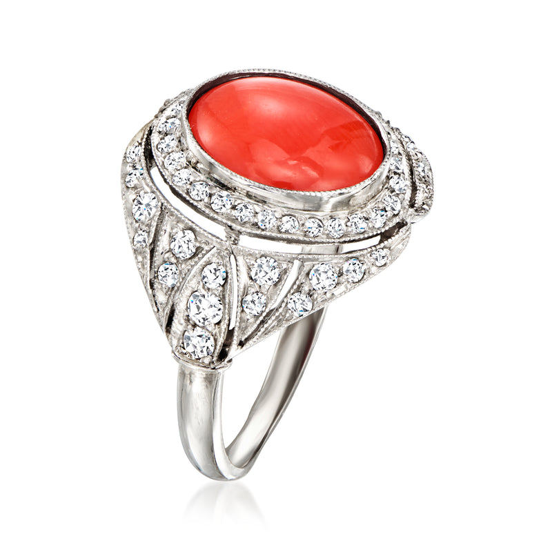 Platinum ring featuring oval coral cabochon with diamond halo and decorative sides