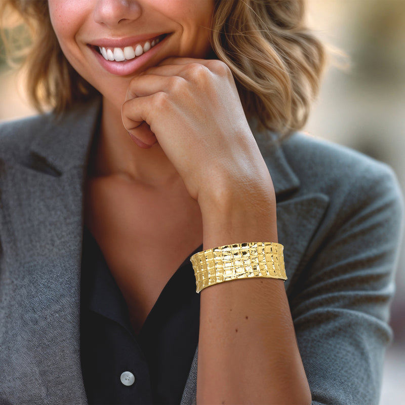 Gold-tone grid-pattern cuff bracelet on wrist, wide open bracelet band