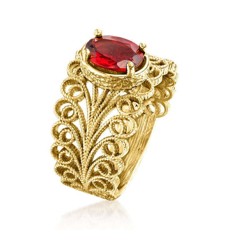 Gold filigree ring with large oval red gemstone and textured scrollwork band.