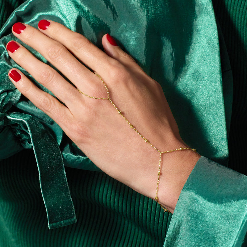 14kt yellow gold beaded hand chain bracelet worn on hand with dangling teardrop