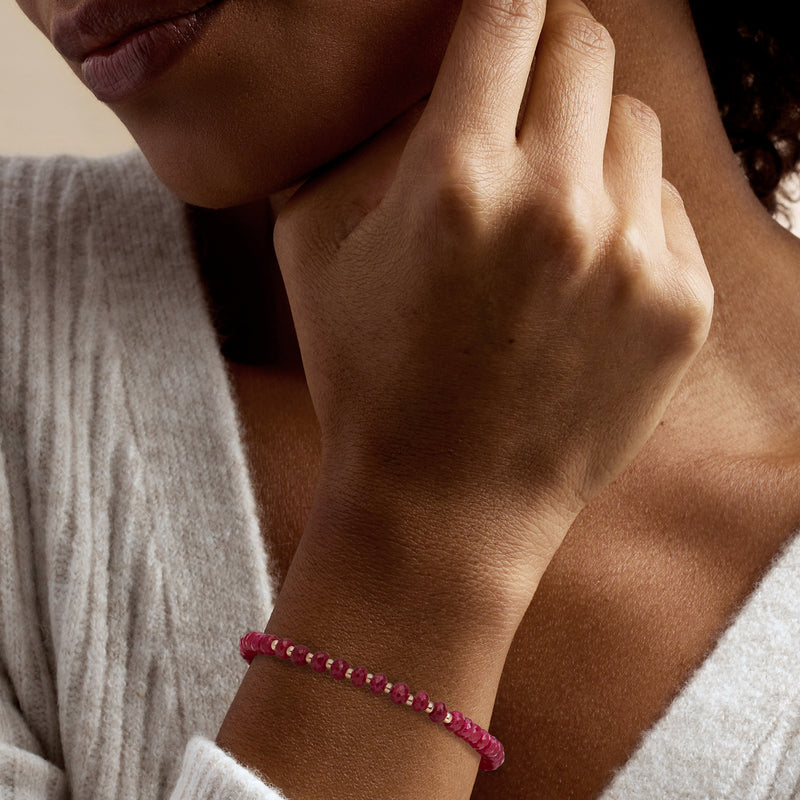 Ruby bead bracelet on wrist, maroon faceted beads with 10kt yellow gold clasp