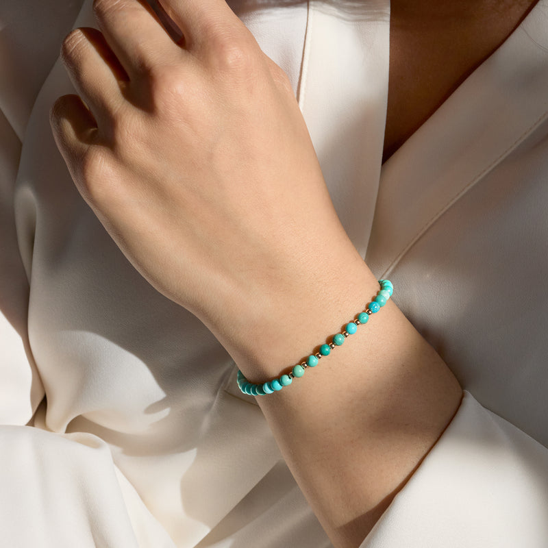 Turquoise bead bracelet with 10kt yellow gold clasp, worn on white dress