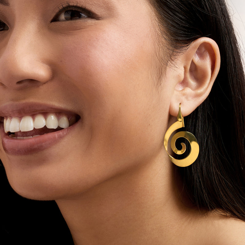Gold spiral drop earrings on ear with fishhook closure and polished circular disc