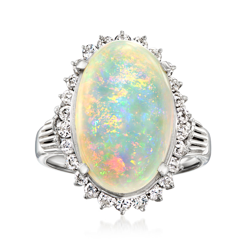 Platinum ring with oval opal cabochon and diamond halo, flanked by small round diamonds