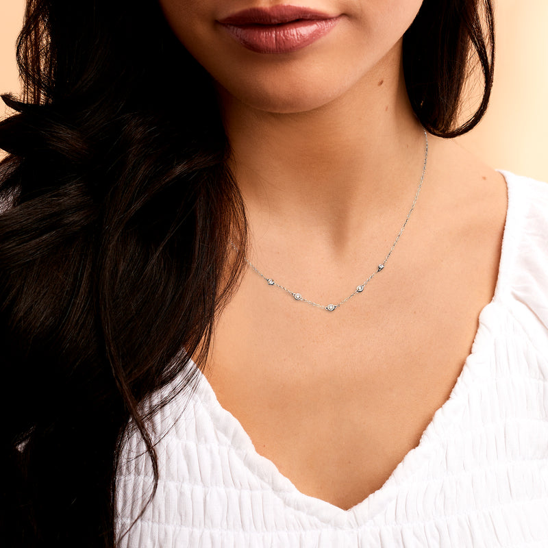 14kt white gold station diamond necklace on model’s neck, fine chain with round stones