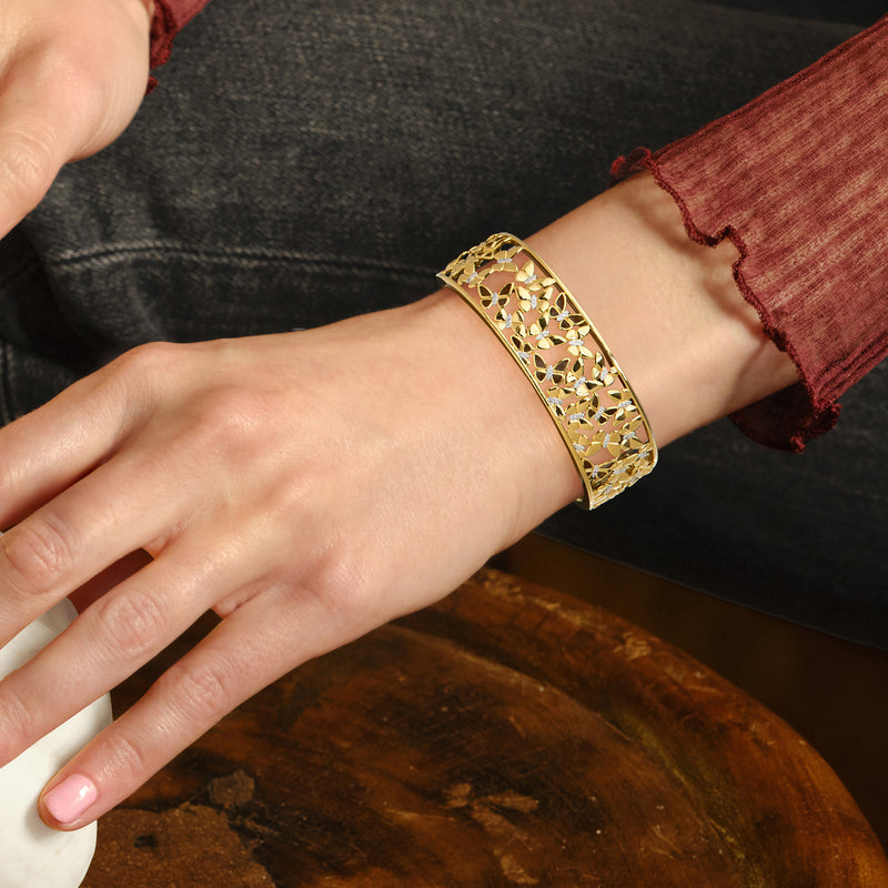 Gold butterfly filigree cuff bracelet on wrist with small diamond accents