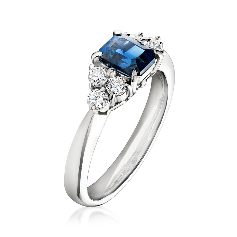 Platinum ring with raised cushion-cut blue sapphire and sparkling diamond accents