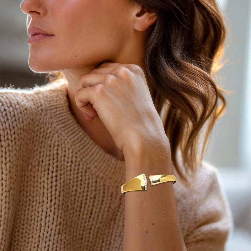 Asymmetrical gold cuff bracelet with polished open design on a woman's wrist
