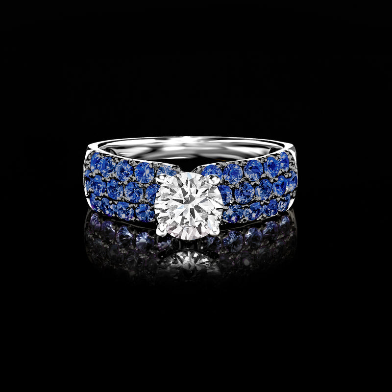 White gold ring with round center diamond and deep blue sapphire channel-style design
