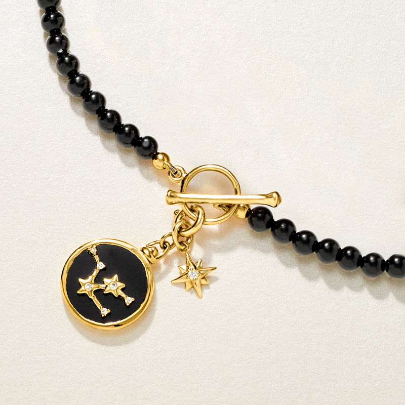 14kt yellow gold star charm with small diamond on black beaded bracelet