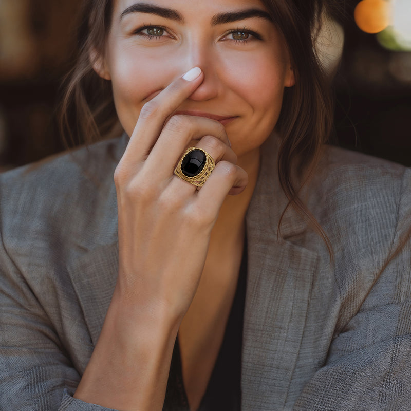Gold-tone roped onyx ring on finger, oval black cabochon visible