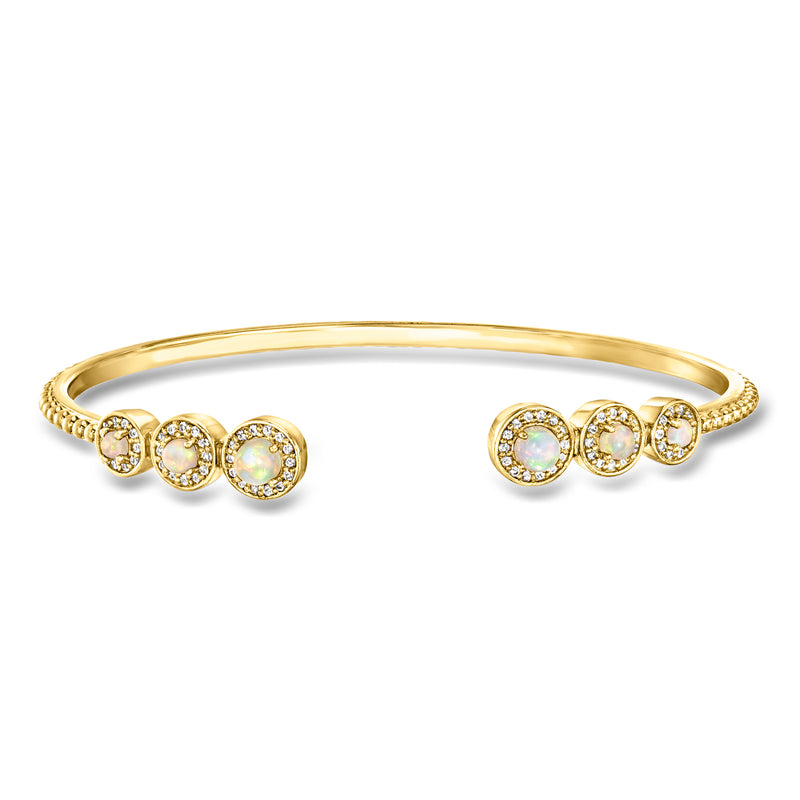 Gold cuff bracelet with five opal-like white stones in halo settings