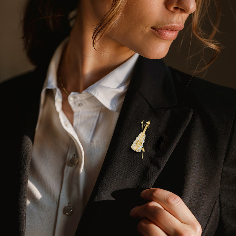 Violin-shaped 18kt yellow gold diamond pin worn on a black blazer lapel