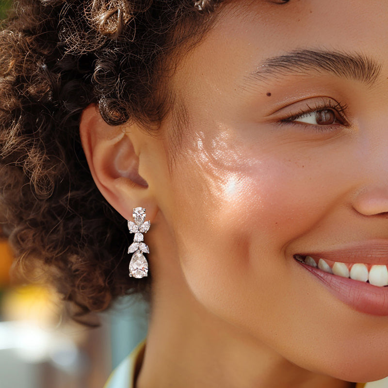 Diamond drop earrings with three pear-cut stones, worn on model's ear