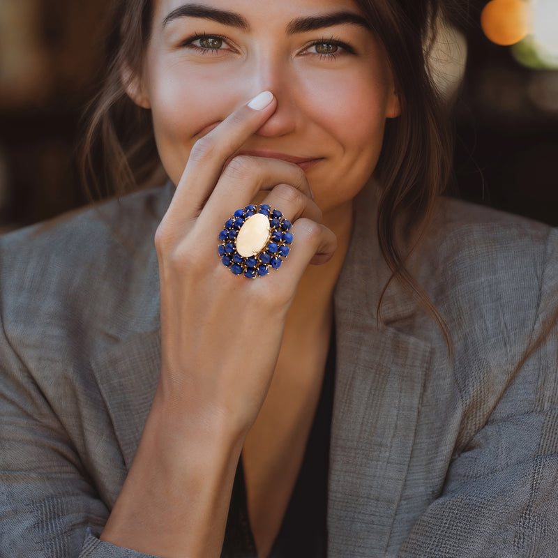 Blue lapis and gold cocktail ring with oval center stone on finger