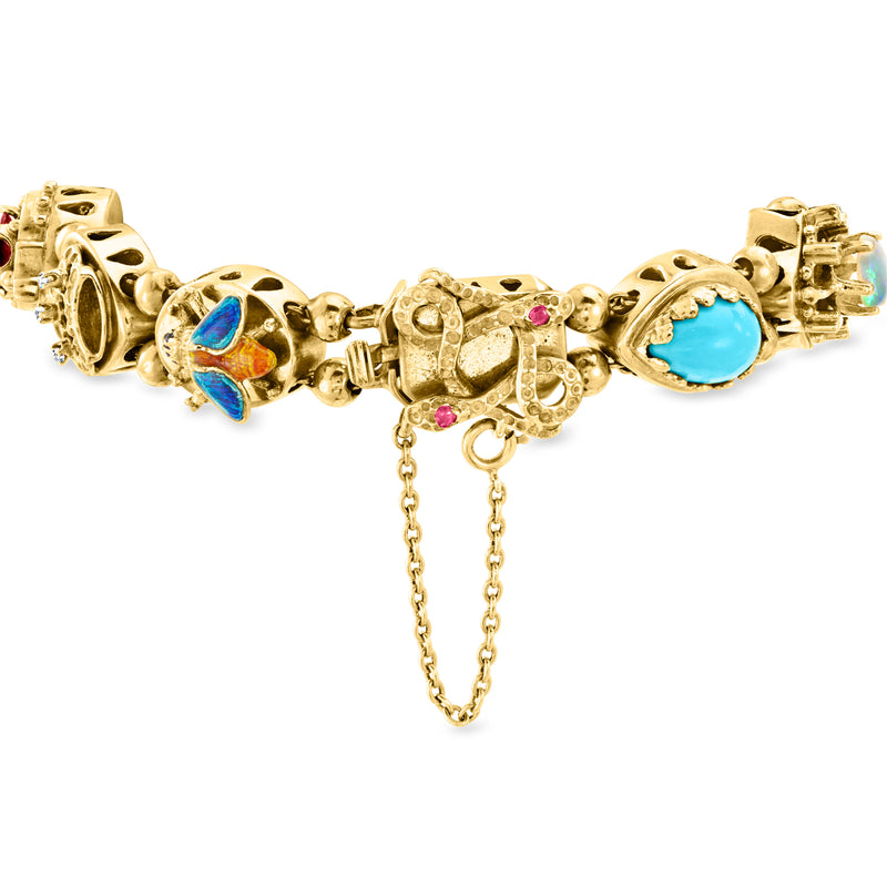 Yellow gold bracelet with oval blue enamel charm, multicolor gem links, and dangling chain tassel