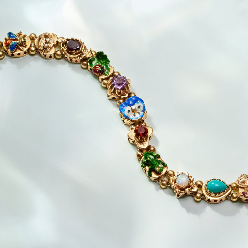 Yellow gold bracelet featuring floral blue, purple, and green gemstone and enamel links