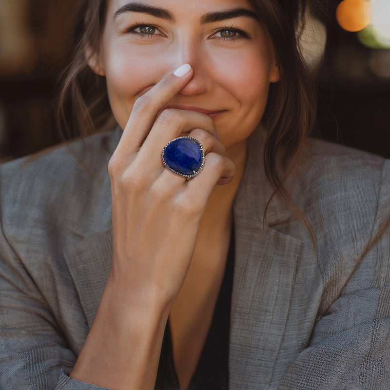 Sterling silver oval lapis ring with zircon halo, worn on hand