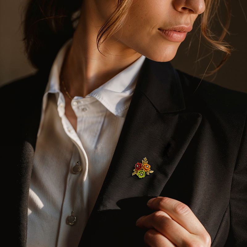 Enamel floral lapel pin on dark blazer with red and green enamel