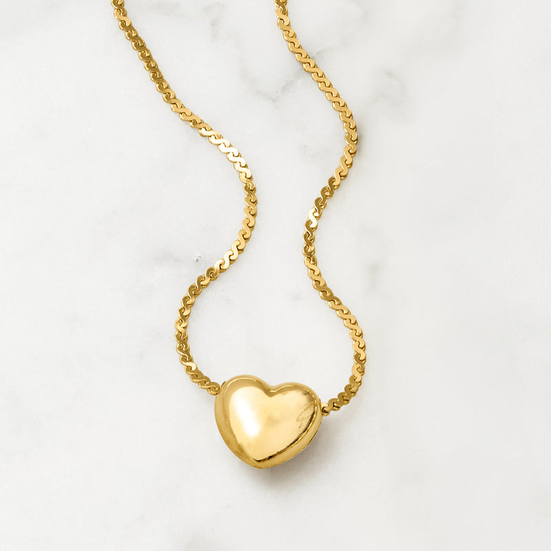 Gold heart pendant necklace close-up, puffed heart at center on curb chain