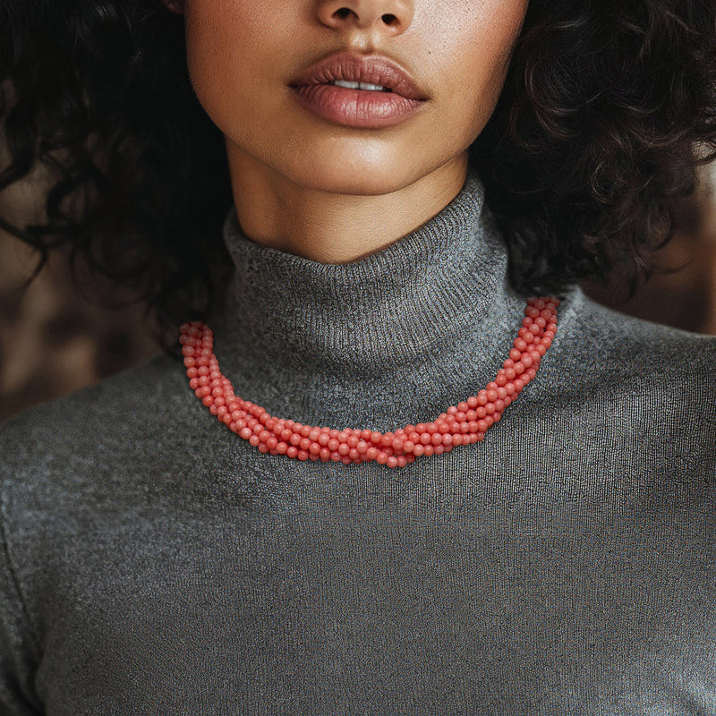 Pink coral bead torsade necklace worn as a short collar