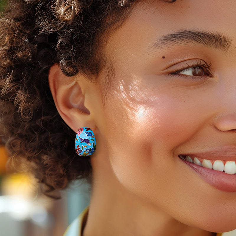 Woman wearing multicolored enamel manta ray hoop earrings in sterling silver