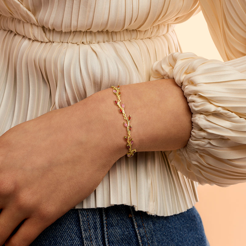 Gold leaf bolo bracelet with pink and red gemstone links on wrist
