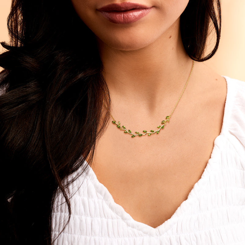 Gold leaf gemstone necklace with green stones, worn at the collarbone