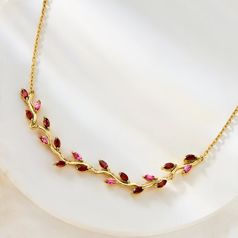 Gold leaf necklace featuring red garnet and pink topaz marquise stones