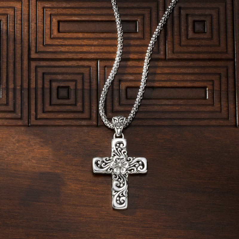 Silver cross pendant necklace with engraved scrollwork floral center on long chain