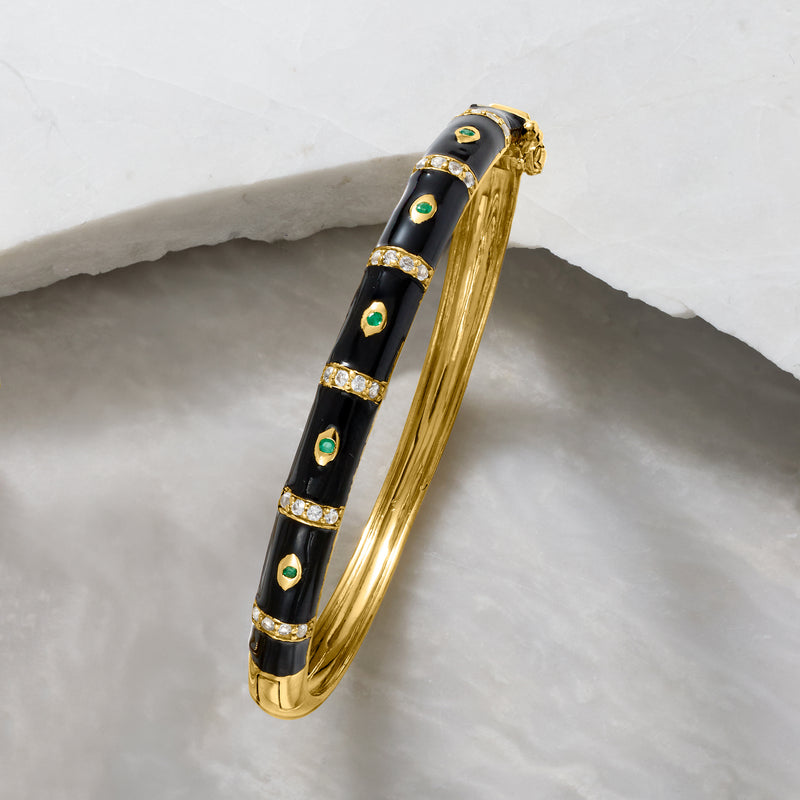 Close-up gold evil eye bangle: black enamel with white topaz bezels and green stones