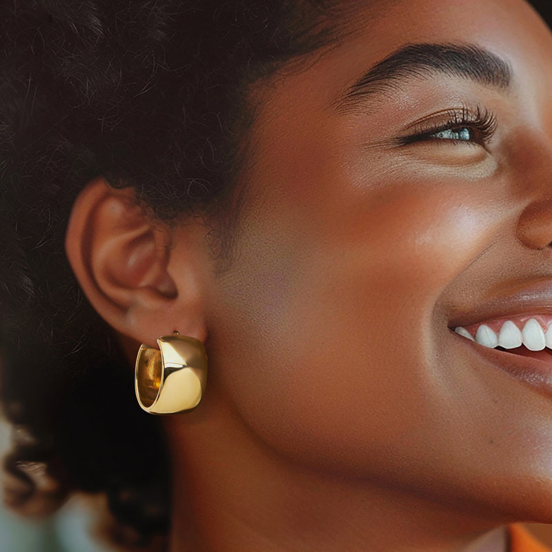 Gold hoop earrings on ear, polished rounded hoops with clasp detail