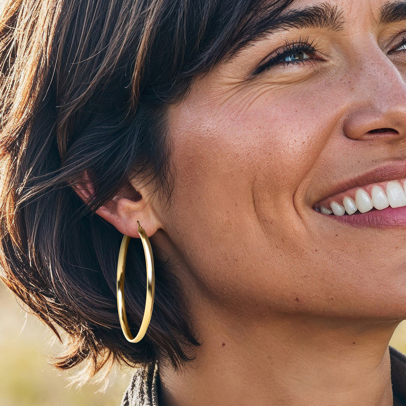 Gold hoop earrings on model, round flat hoops with hinge at top