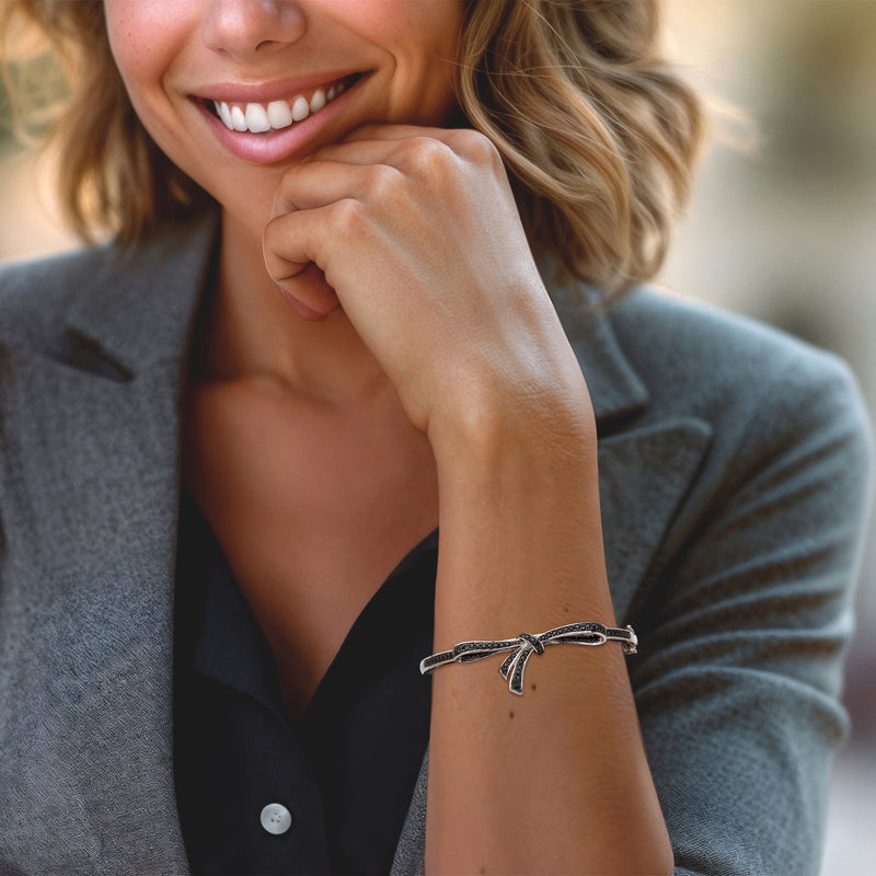 Sterling silver bow bangle bracelet on wrist with black stone bow detail