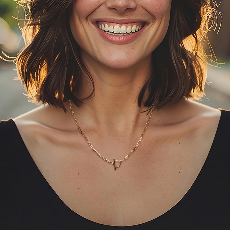 Gold necklace worn by model, featuring small turquoise sunflower pendant on toggle clasp