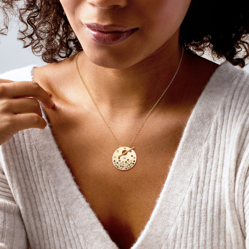 Gold-tone toggle necklace on model with round multicolor gemstone pendant