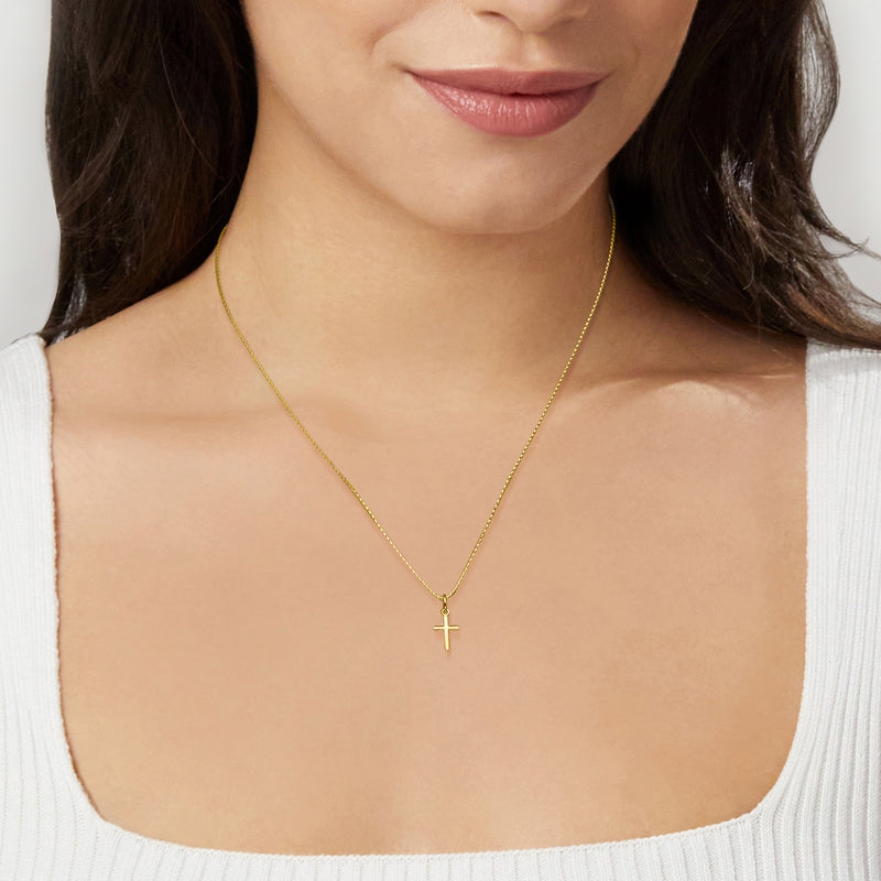 Petite cross pendant on a 10k yellow gold chain necklace, worn