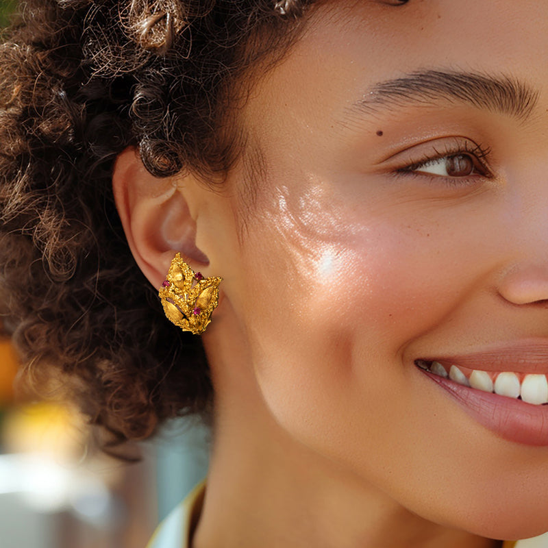 Textured gold floral clip-on earrings with pink stones on ear