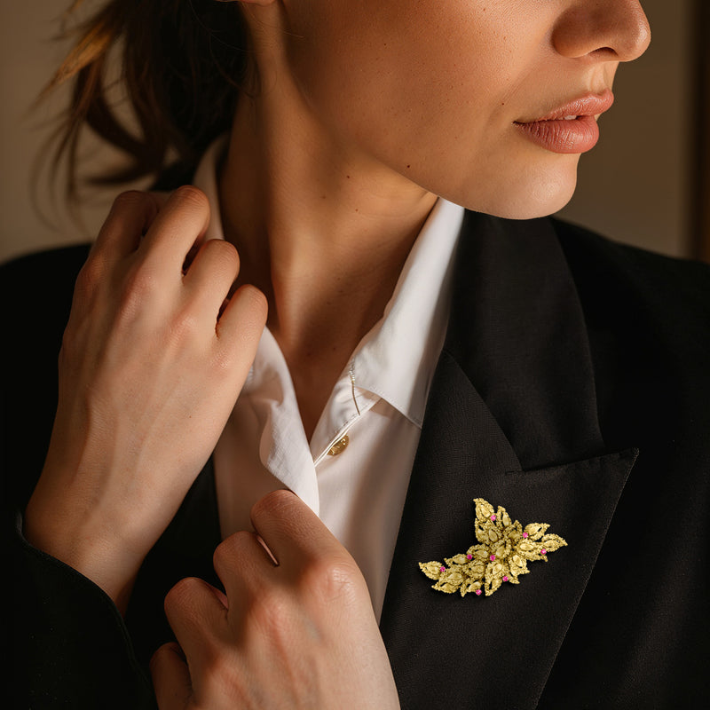 Floral ruby pin in 18kt yellow gold with pink stones, worn on lapel