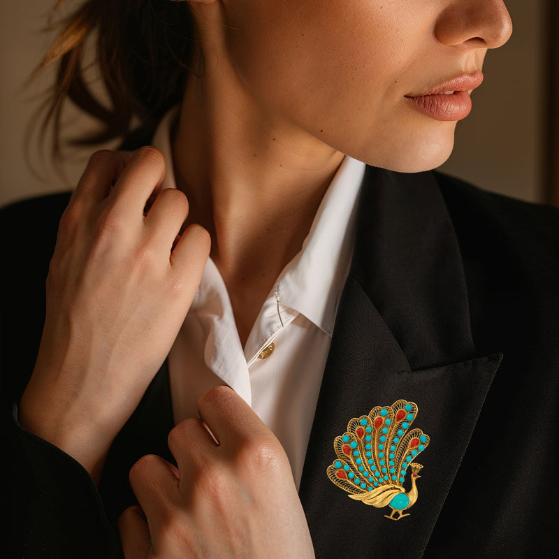 Gold peacock pin with turquoise and red stones on blazer lapel