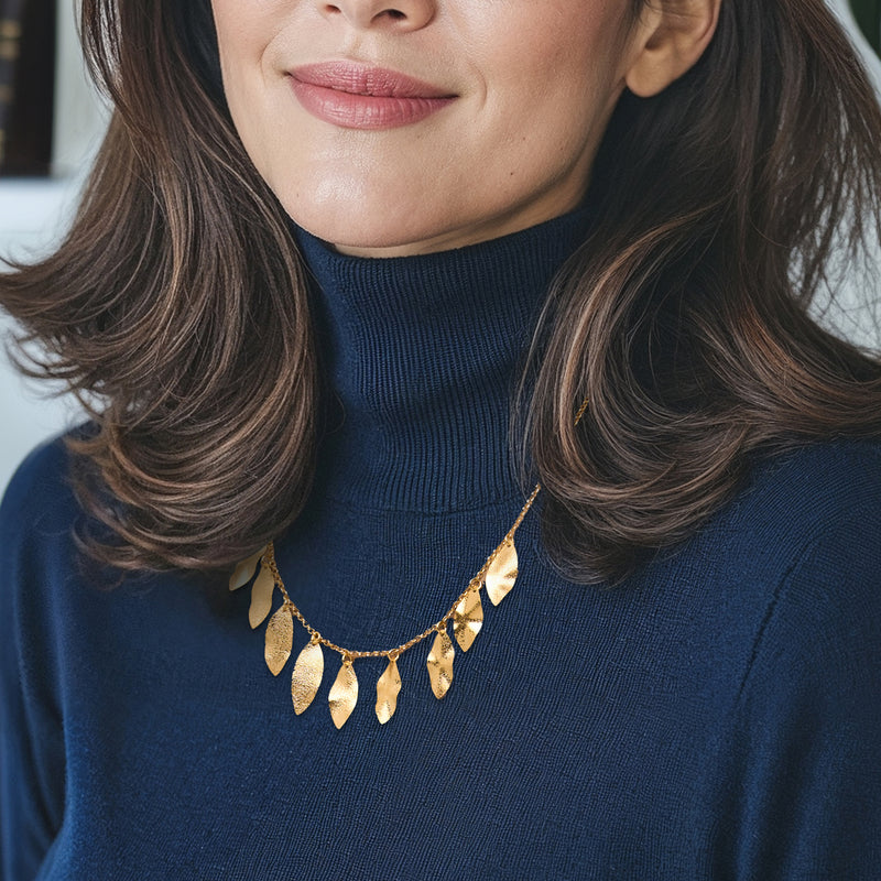 Gold leaf station necklace with dangling teardrop leaf charms, worn at collarbone