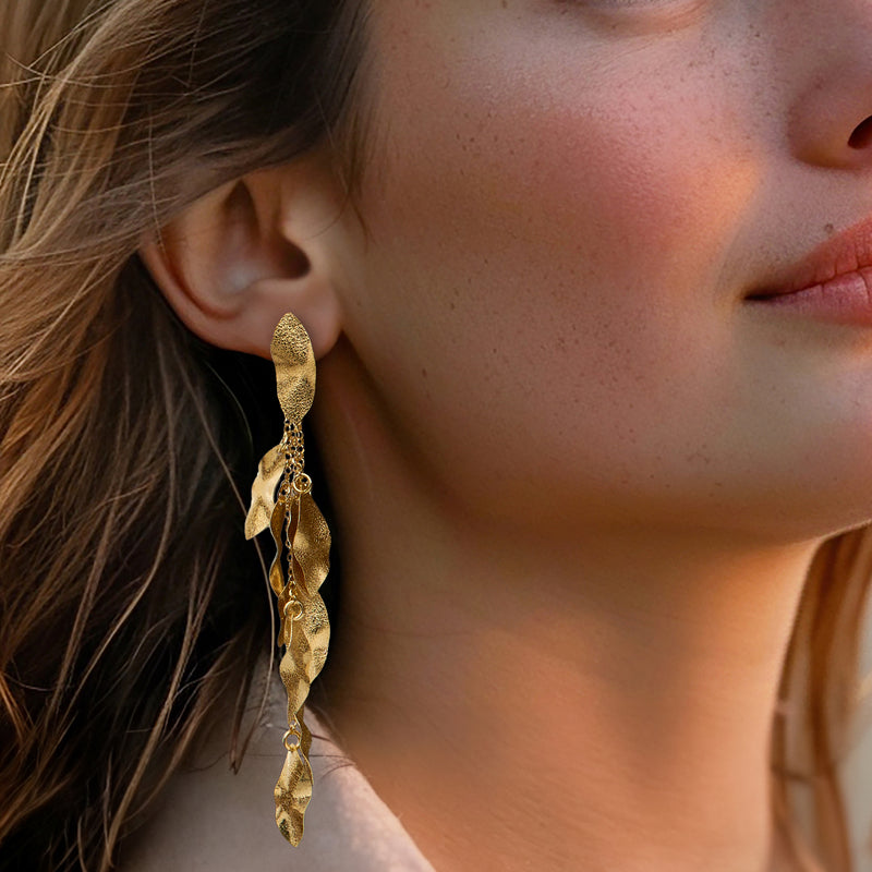 Gold-tone textured leaf drop earrings worn, featuring dangling leaf charm and chain